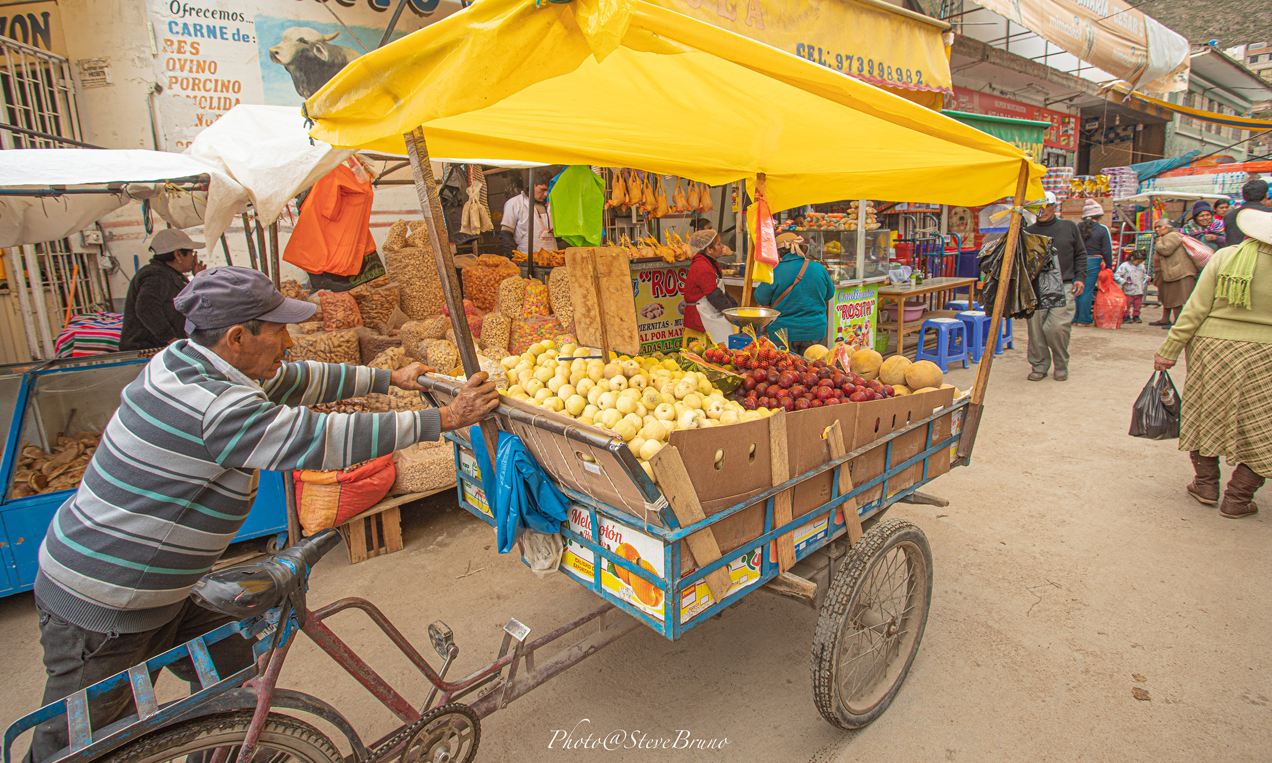 A man pushes a card of produce in Peru