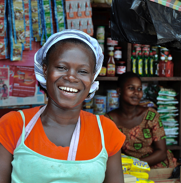 Smiling woman in front of market stall in Ghana