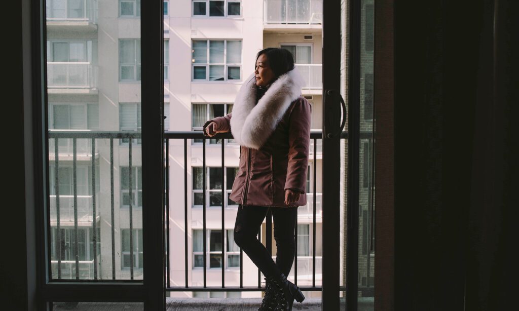 A woman in a parka stands on a balcony